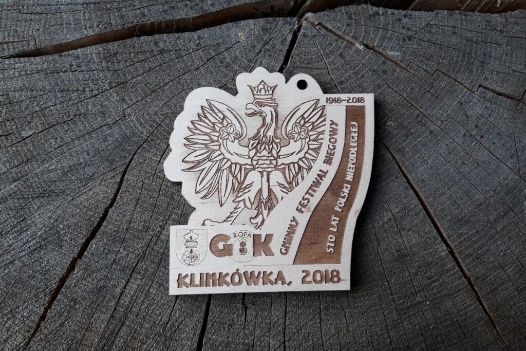 Drewniany medal patriotyczny na Gminny Festiwal Biegowy Klimkówka 2018 z wygrawerowanym orłem oraz flagą Polski.
