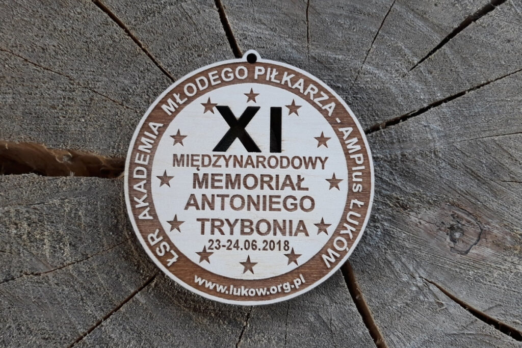 Drewniany medal sportowy na XI Międzynarodowy Memoriał Antoniego Trybonia z wyciętą na wylot ażurowo cyfrą XI