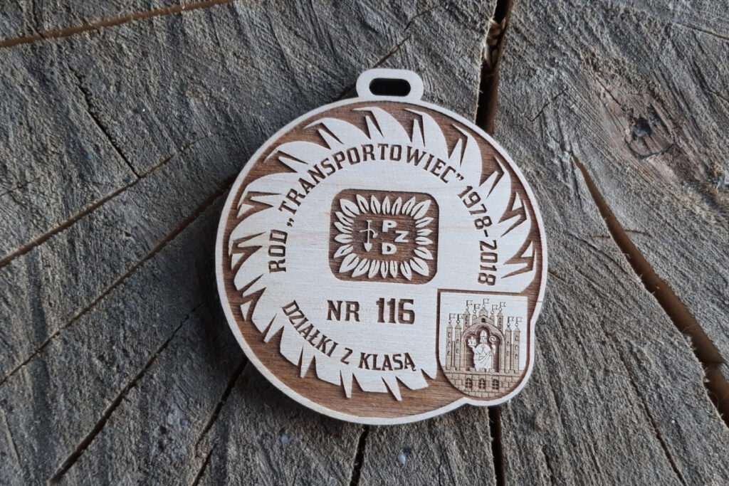 Okrągły drewniany medal jubileuszowy RPD Transportowiec 1978-2018 z grawerem logotypu i napisem "Działki z klasą" i logiem.