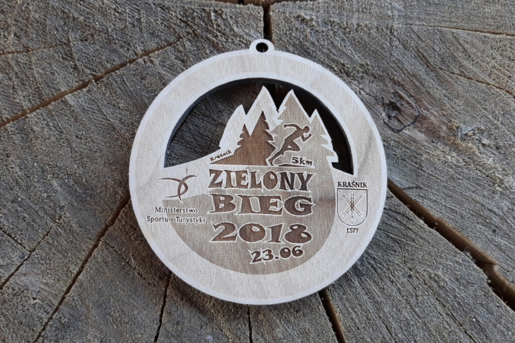 Ekologiczny medal z drewna z precyzyjnymi ażurowymi wycięciami, przygotowany na imprezę sportową Zielony Bieg.