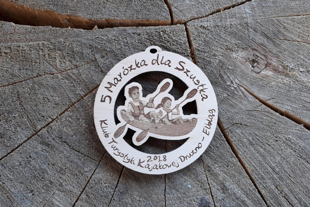 Drewniany medal ażurowy na spływ kajakowy „5. Marózka dla Szóstka” z wyciętym motywem kajakarzy.