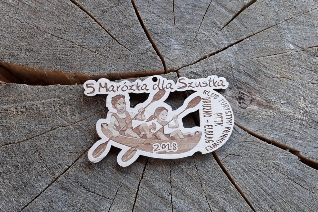 Drewniany okrągły medal na 5. spływ kajakowy rzeką Marózką z grawerem logotypu i napisem pamiątkowym.