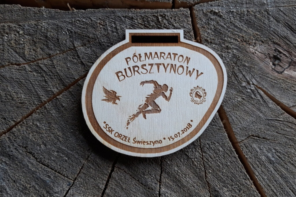 Drewniany medal na Półmaraton Bursztynowy z grawerem logotypu wydarzenia i biegaczem.