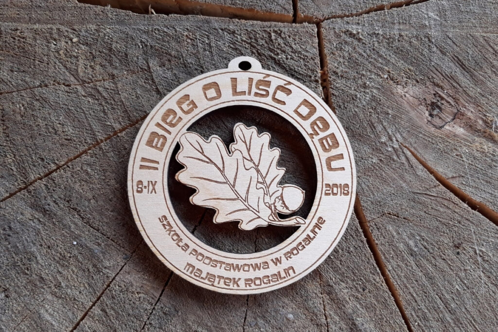 Ażurowy drewniany medal na II Bieg o Liść Dębu z precyzyjnie wyciętym motywem liścia i żołędzia.