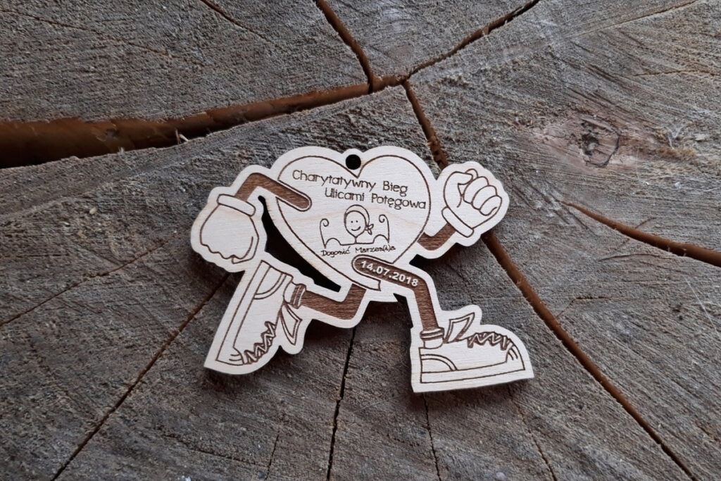 Medal z drewna w formie "biegnącego serca" z grawerem logotypu Potęgowa i napisem pamiątkowym.