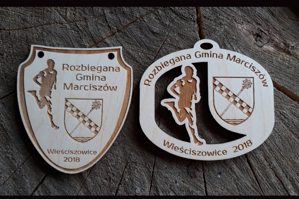 Drewniany medal sportowy Rozbiegana Gmina Marciszów z wygrawerowanym herbem gminy i biegaczem. Propozycja 2 medali.