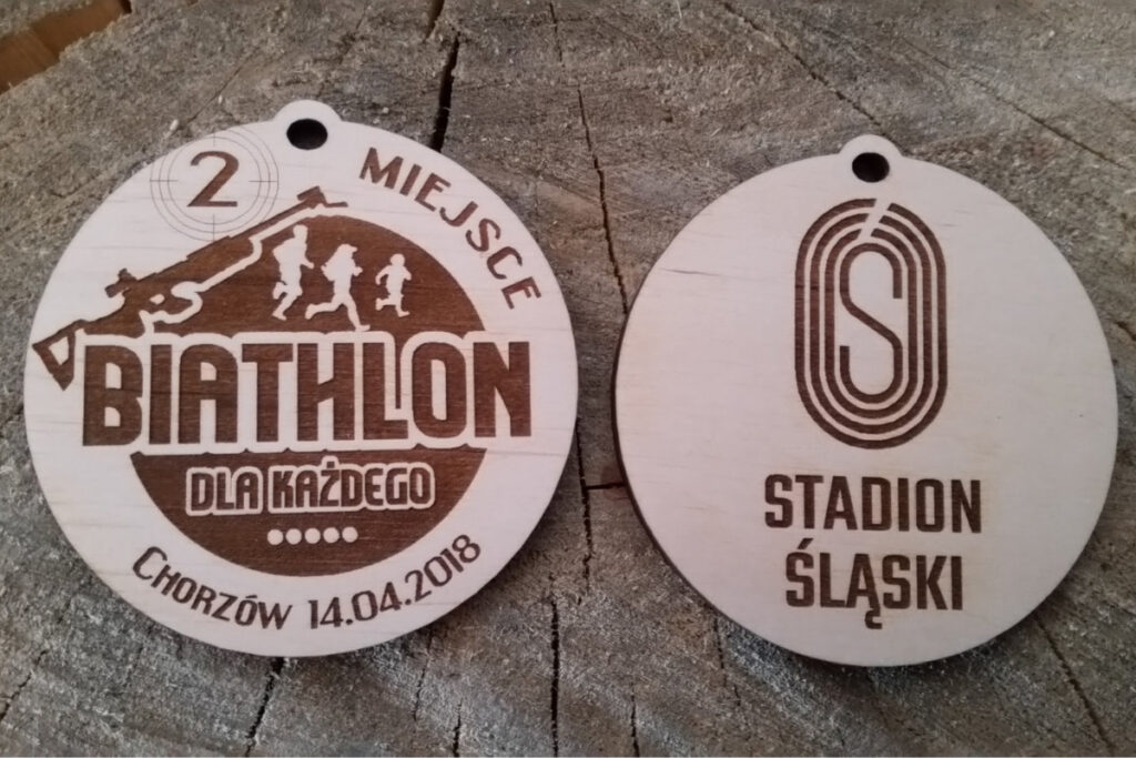 Okrągły drewniany medal z napisem Biathlon dla każdego.