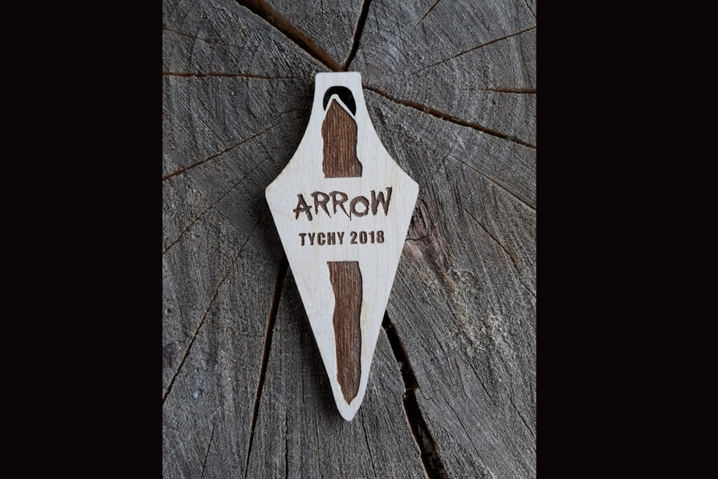 Drewniany medal pamiątkowy Arrow Tychy z grawerowaną strzałą i rokiem wydarzenia.