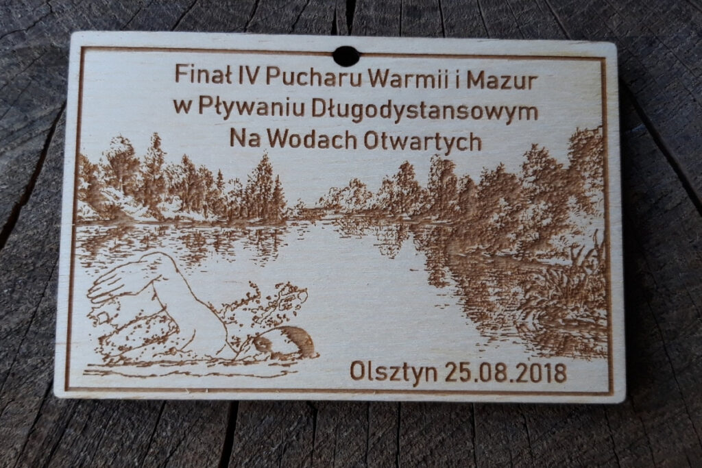 Drewniany medal na Finał IV Pucharu Warmii i Mazur w pływaniu długodystansowym z grawerem pływaka na otwartej wodzie.