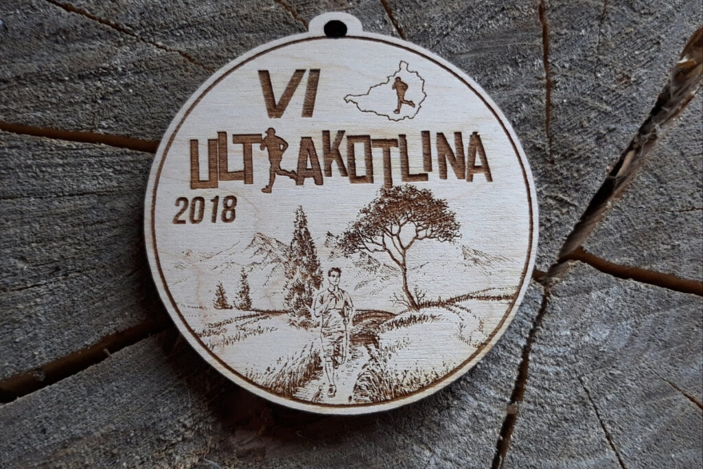 Drewniany medal na VI Ultrakotlinę z grawerem panoramy górskiej i dystansów ultra.