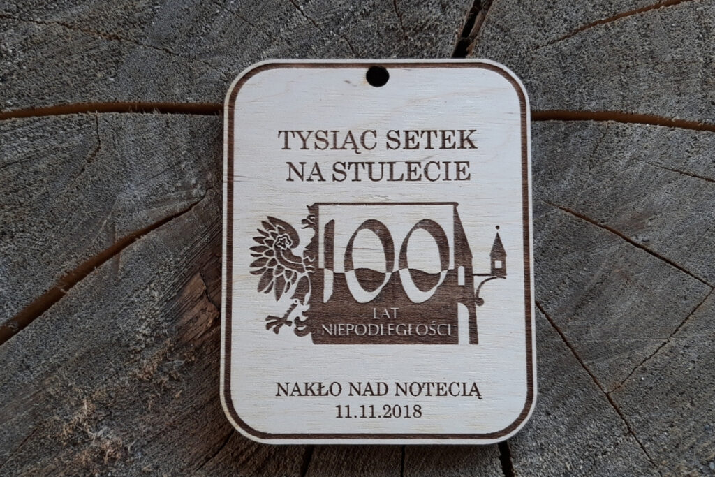 Drewniany medal patriotyczny na 100-lecie Niepodległości z grawerem polskiego godła i napisem Tysiąc Setek na fladze Polski
