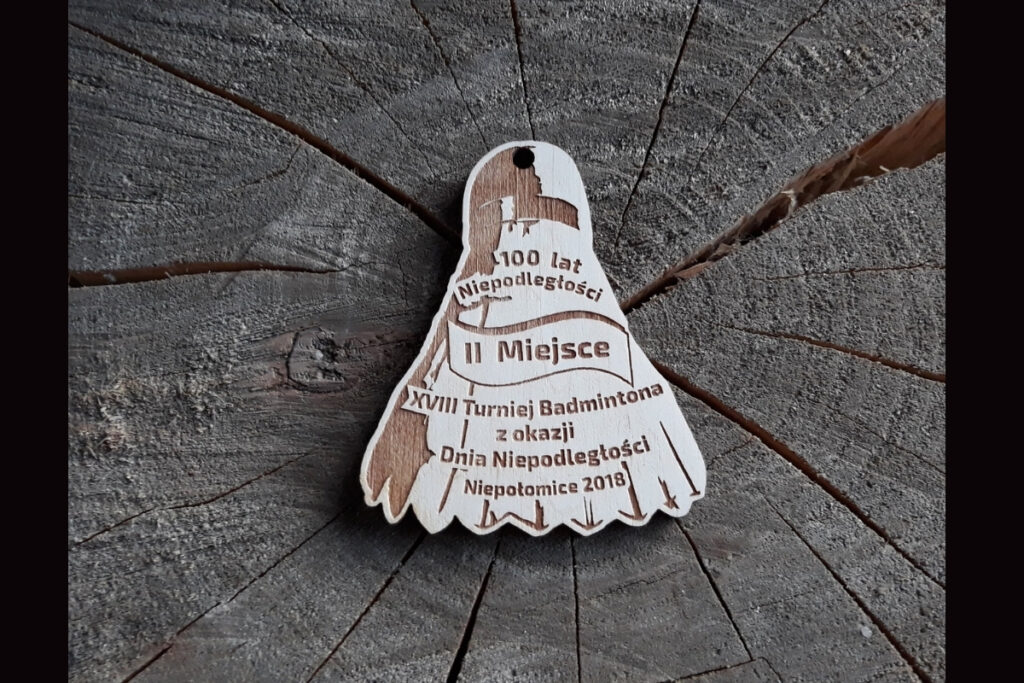 Drewniany medal w kształcie lotki do badmintona na XVIII Turniej z okazji Dnia Niepodległości.