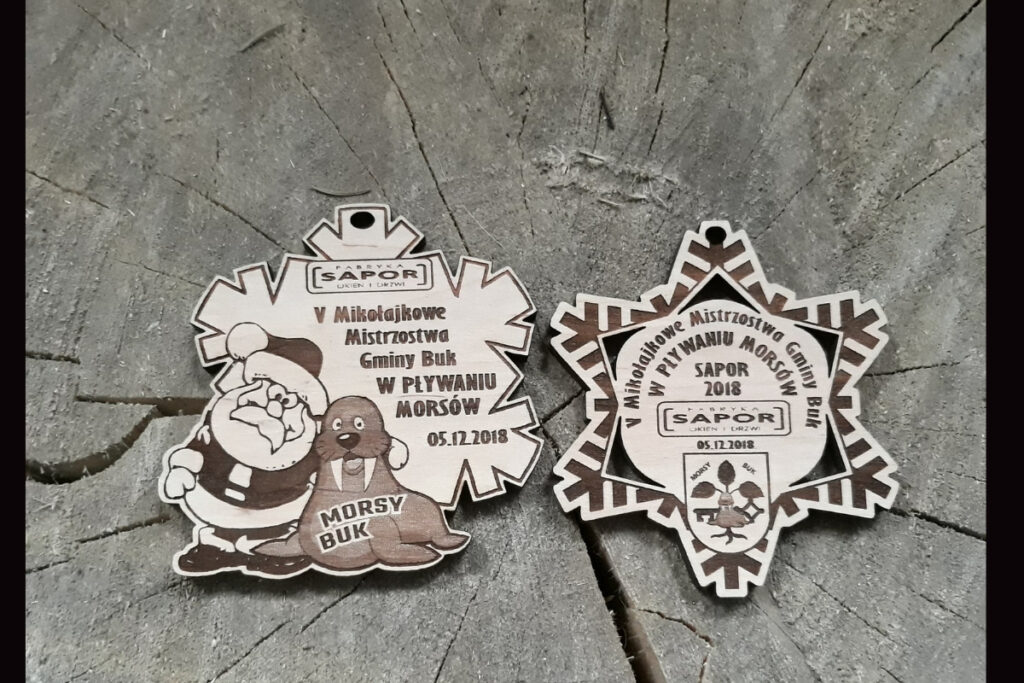 Drewniany medal na Mikołajkowe Mistrzostwa Gminy Buk w pływaniu morsów z nieregularnymi wycięciami.