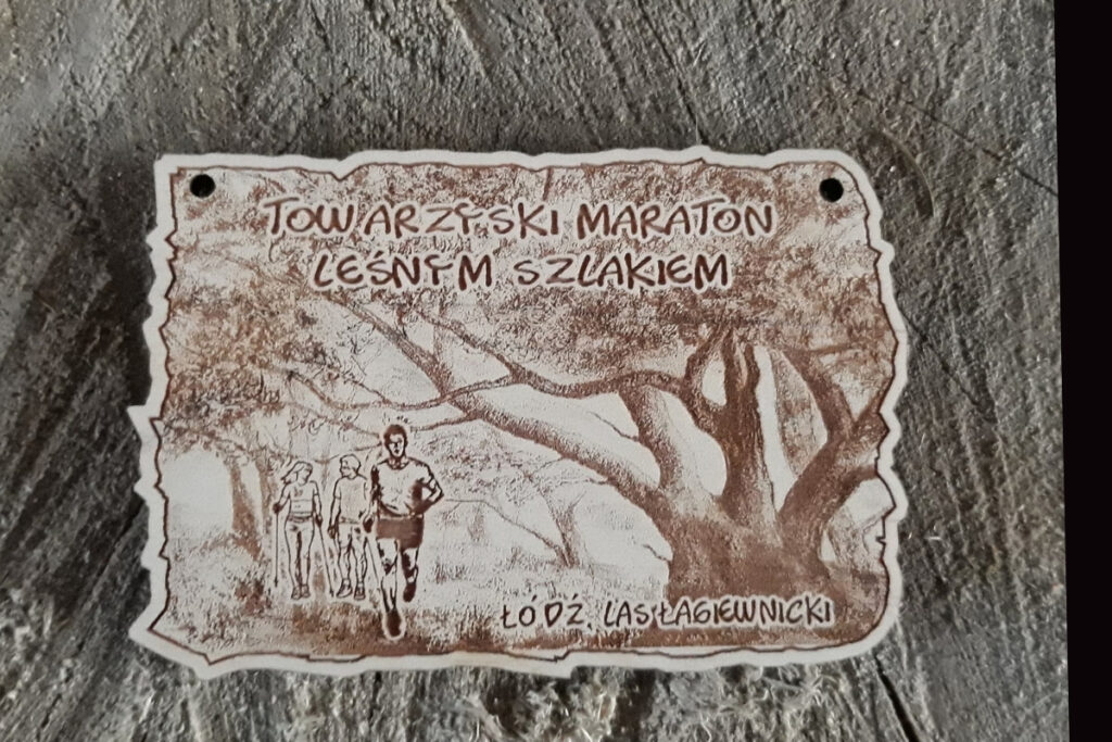 Drewniany medal na Towarzyski Maraton Leśnym Szlakiem z grawerem drzew drzewa, biegaczy i zawodników NW.
