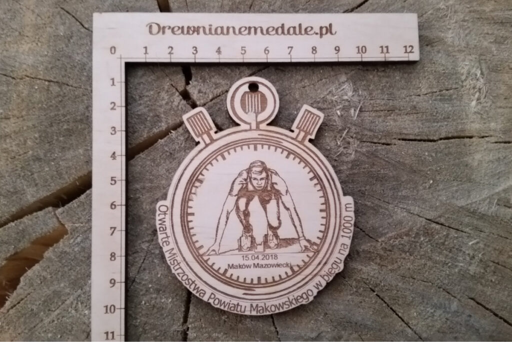 Drewniany medal sportowy z grawerem biegacza na bieżni lekkoatletycznej, zawieszony na ekologicznym sznurku.