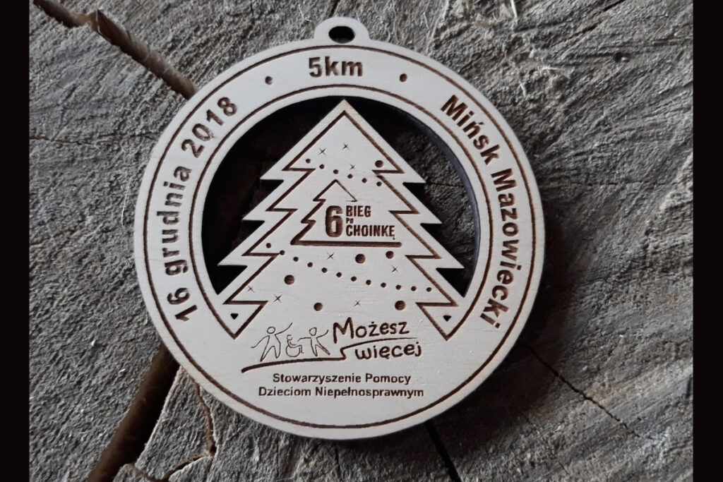 Ażurowy drewniany medal na 6. Bieg po Choinkę z wyciętym laserowo kształtem choinki i grawerem.