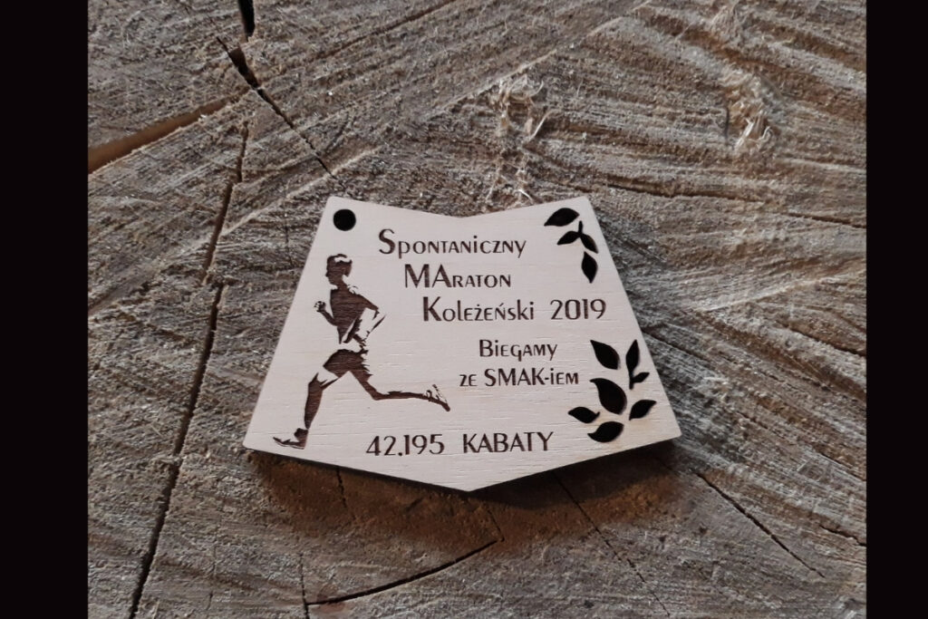 Drewniany medal na Spontaniczny Maraton Koleżeński "Biegamy ze Smak-iem" z grawerem biegacza i biegnącej postaci.
