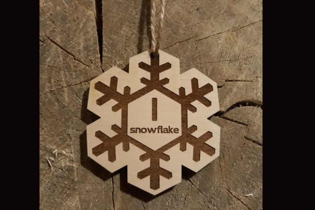 Drewniany medal w kształcie śnieżynki „Snowflake” z precyzyjnymi ażurowymi wycięciami.