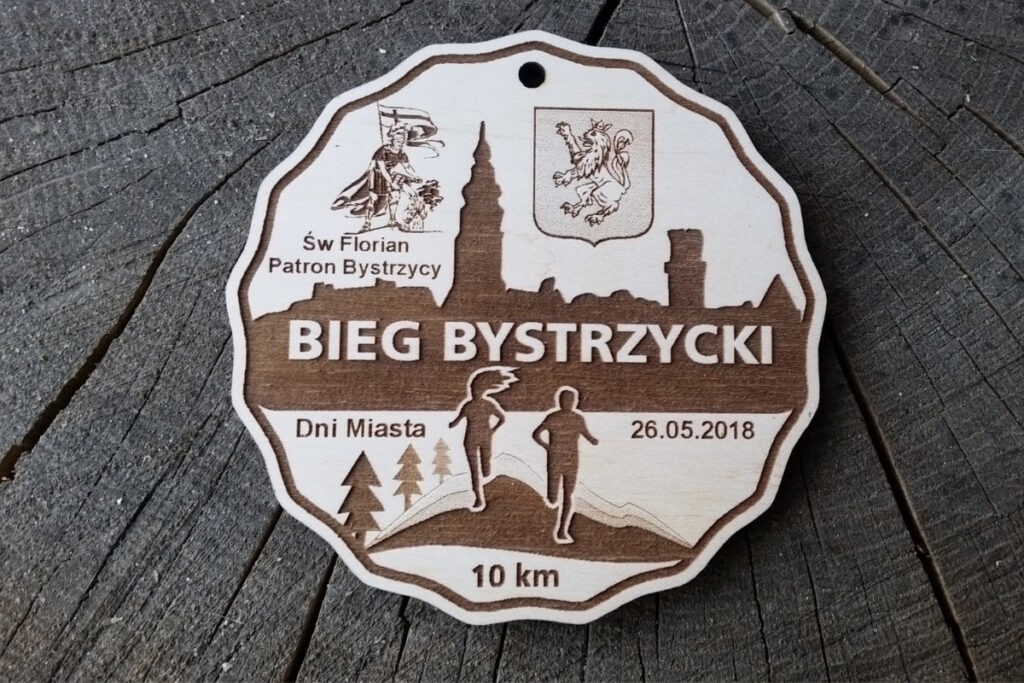 Ekologiczny drewniany medal na Bieg Bystrzycki z grawerowanym motywem biegacza i lasu, zawieszony na jutowym sznurku.