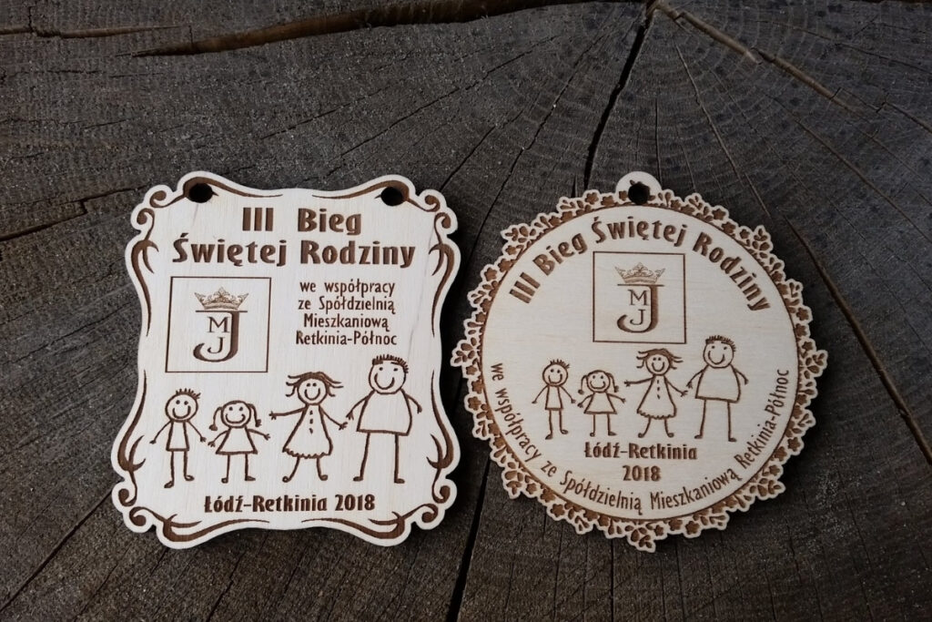 Projekty drewnianych medali na III Bieg Świętej Rodziny z grawerowaną sylwetką rodziny i detalami, zawieszony na ekologicznym sznurku.