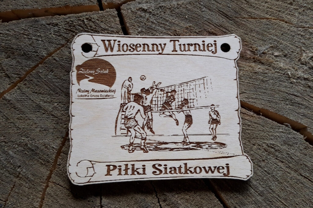Drewniany medal na Wiosenny Turniej Piłki Siatkowej z grawerem piłki do siatkówki przelatującej nad siatką oraz graczami po obu stronach siatki.
