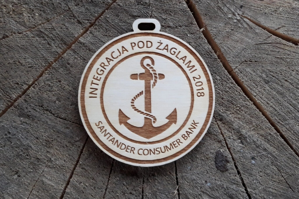 Okrągły drewniany medal "Integracja pod żaglami 2018" z grawerowaną kotwicą.