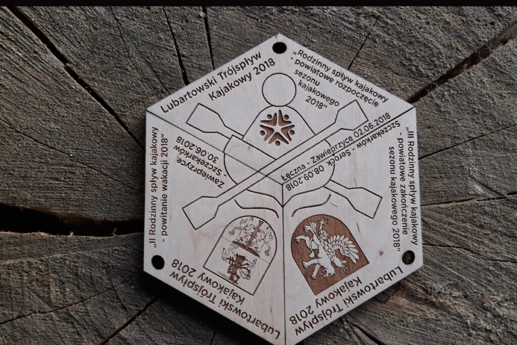 Zestaw trzech drewnianych medali o tematyce kajakowej, które po złożeniu tworzą spójną tabliczkę. Na powierzchni znajduje się grawerowana laserowo grafika przedstawiająca kajakarza na rzece.