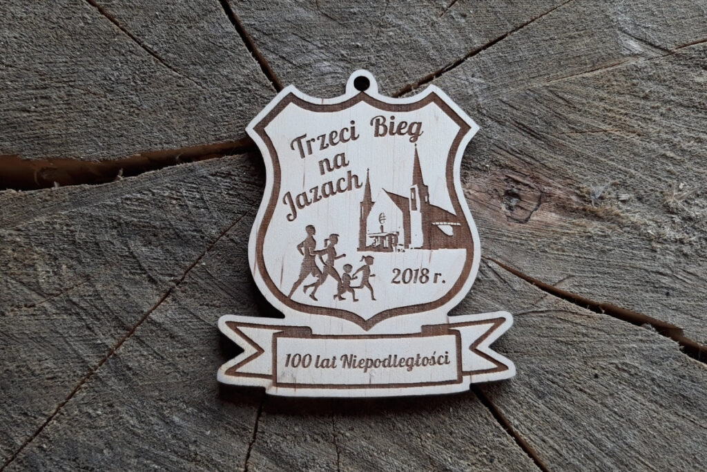 Medal wykonany z jasnego drewna z grawerem laserowym. W górnej części znajduje się napis 'III Bieg na Jazach'.