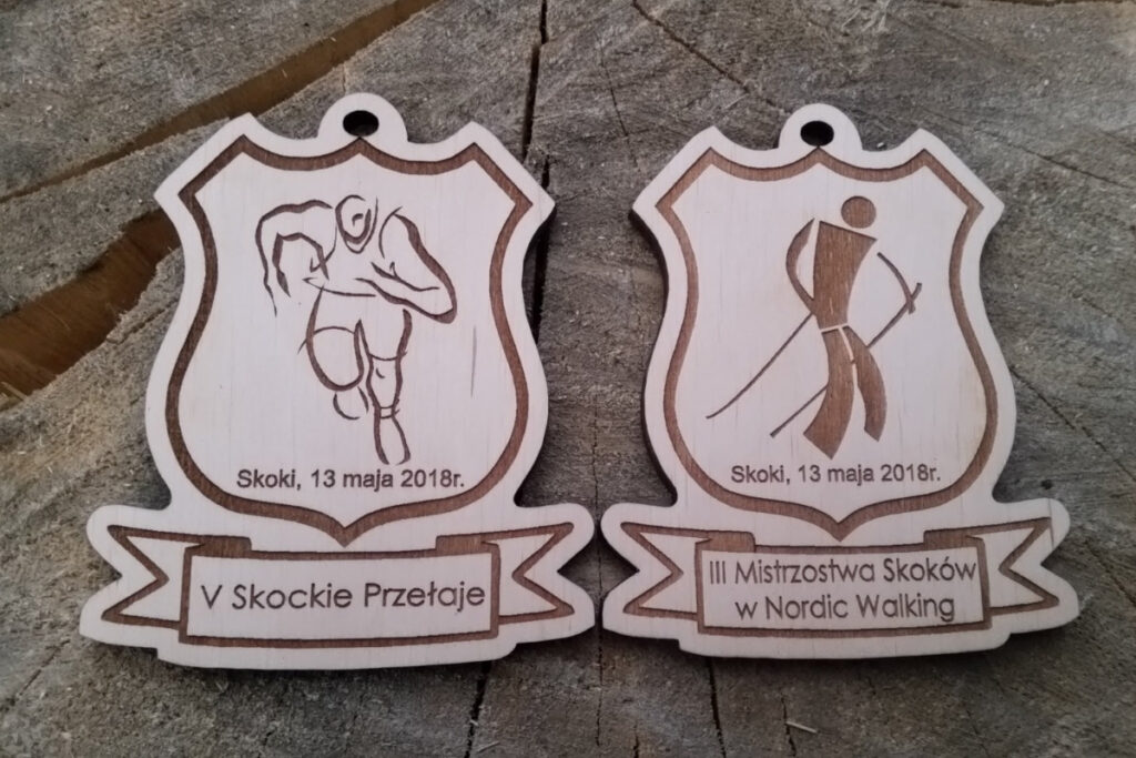 Drewniane medale z grawerem „Skockie Przełaje”, przedstawiające sylwetkę biegacza i uczestnika Nordic Walking