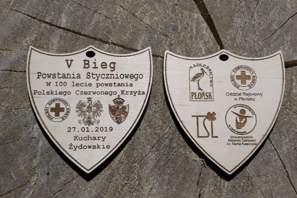 Dwustronny drewniany medal na V Bieg Powstania Styczniowego i 100-lecie Polskiego Czerwonego Krzyża z grawerem historycznym i logotypami.