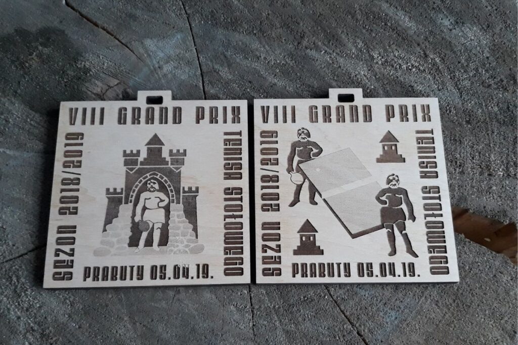 Drewniane medale dwustronne z napisem VIII Grand Prix Prabut w Tenisie Stołowym.