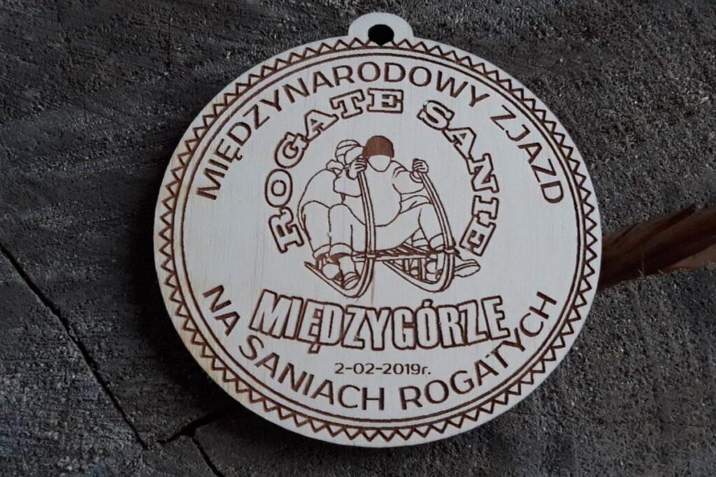 Drewniany medal pamiątkowy z grawerem sań rogatych na Międzynarodowy Zjazd w Międzygórzu.