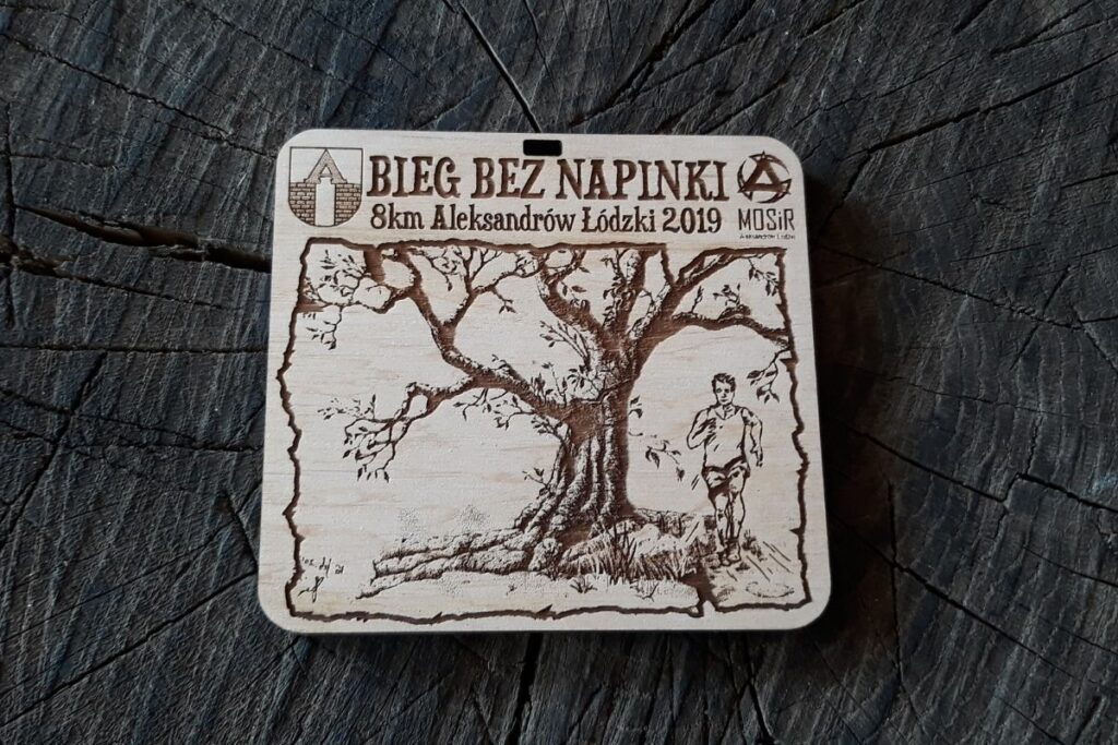 Drewniany medal na Bieg Bez Napinki w Aleksandrowie Łódzkim z grawerem drzewa i biegacza, napisami, oraz logo wydarzenia.
