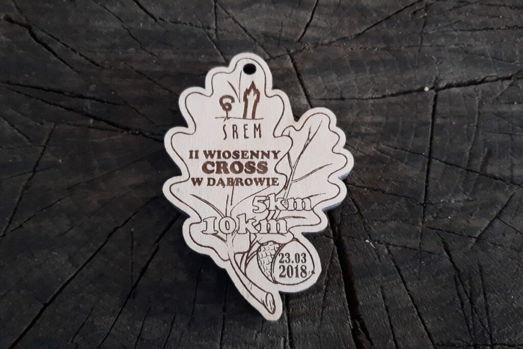 Drewniany medal w kształcie liścia dębu na II Wiosenny Cross w Dąbrowie.