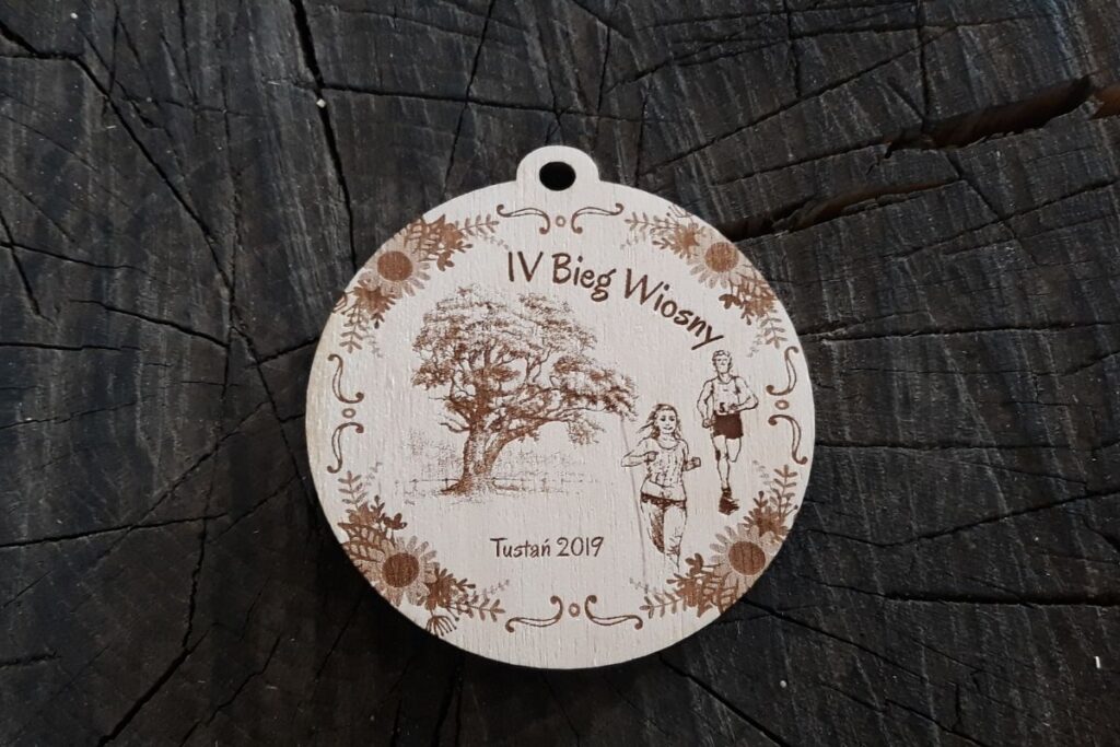 Pamiątkowy medal drewniany z motywem wiosennym i precyzyjnym grawerem daty oraz miejsca wydarzenia.