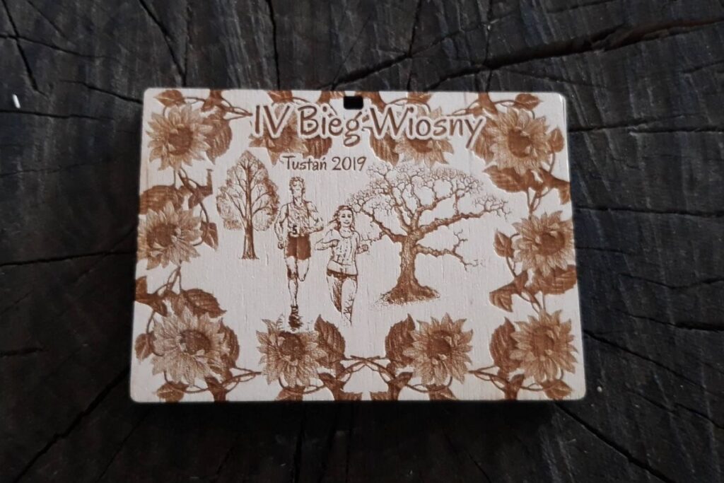 Pamiątkowy medal drewniany z motywem wiosennym i precyzyjnym grawerem daty oraz miejsca wydarzenia.