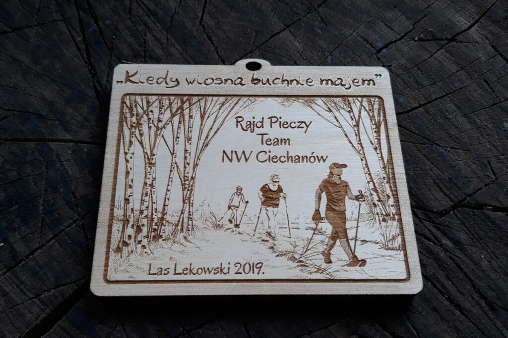Drewniany medal pamiątkowy na rajd pieszy z grawerowanymi detalami, zawieszony na ekologicznym sznurku.