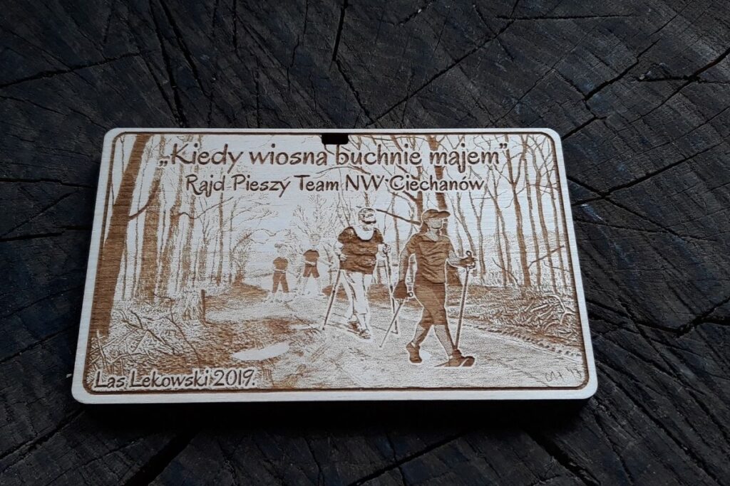 Drewniany medal pamiątkowy na rajd pieszy z grawerowanymi detalami, zawieszony na ekologicznym sznurku.