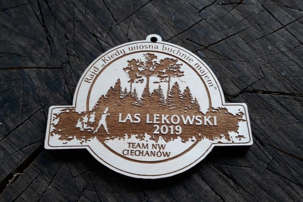 Drewniany medal pamiątkowy na rajd pieszy z grawerowanymi detalami, zawieszony na ekologicznym sznurku.