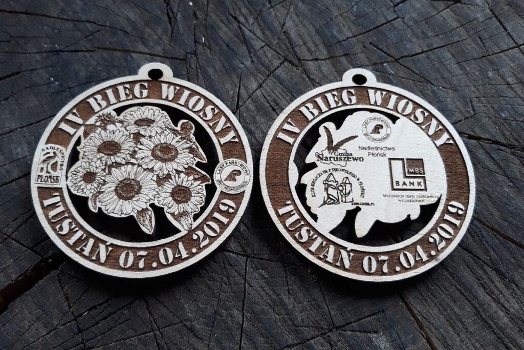 Drewniany medal ażurowy na IV Bieg Wiosny Tuśtan 2019 z wyciętym wzorem i dwustronnym grawerem logotypów.