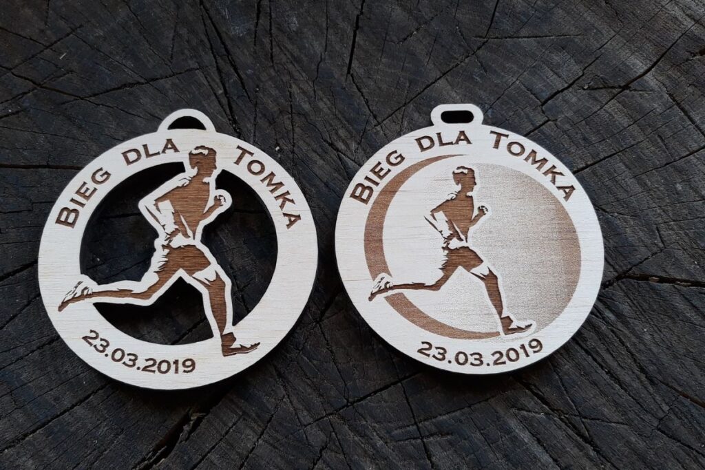 Drewniany medal charytatywny „Bieg dla Tomka” – okrągły wzór ażurowy z sylwetką biegacza.