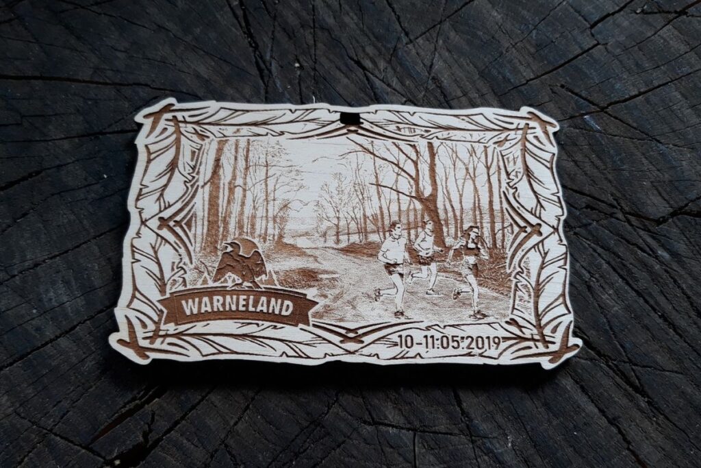 Drewniany medal WarneLand na bieg leśny, grawerowany laserowo z motywem pióra i ptaka.
