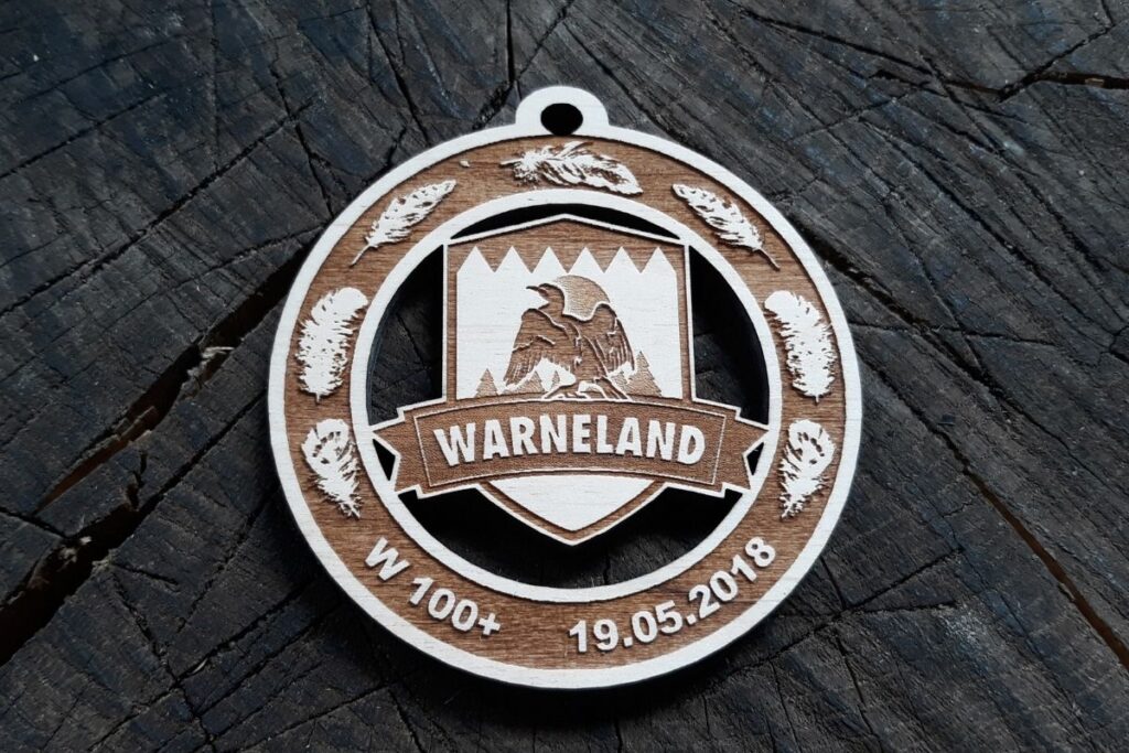 Drewniany medal WarneLand na bieg leśny, grawerowany laserowo z motywem pióra i ptaka.