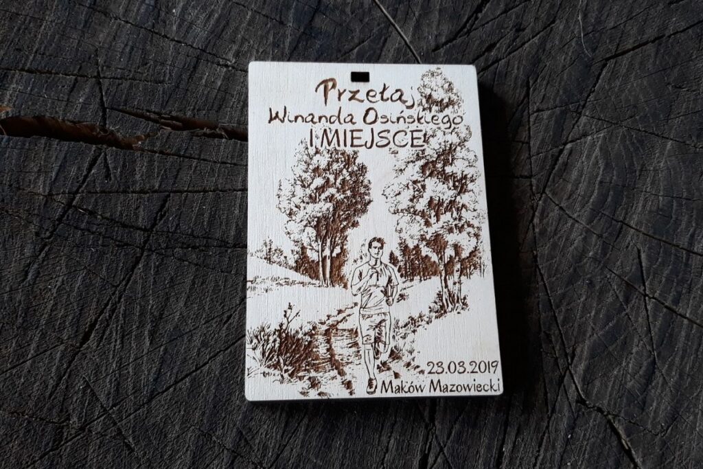 Drewniany medal na Przełaje Winanda Osińskiego, styl crossowy, grawerowany laserowo motyw lasu i biegaczy.