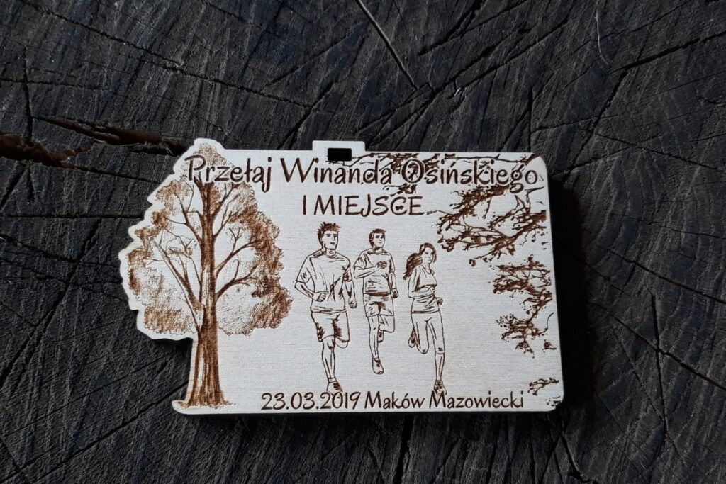 Drewniany medal na Przełaje Winanda Osińskiego, styl crossowy, grawerowany laserowo motyw lasu i biegaczy.