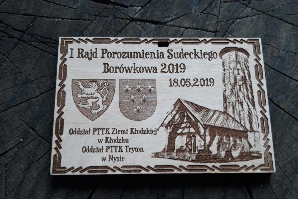 Prostokątny medal z drewna z precyzyjnym grawerem wieży na szczycie Borówkowej, napisami Rajd Porozumienia Sudeckiego i datą 2019.