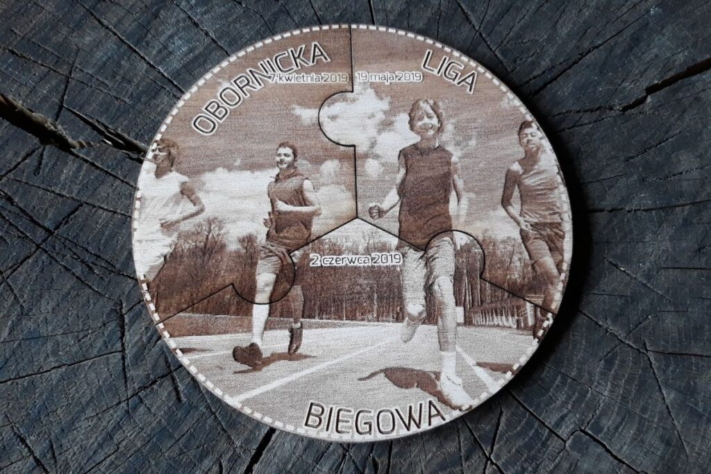 3 drewniane medale które są ze sobą dopasowane w formie puzzli i tworzą grafikę biegnących dzieci.