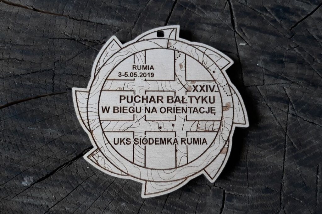 Drewniany medal na XXIV Puchar Bałtyku w Biegu na Orientację, grawerowany laserowo, motyw kompasu i mapy.