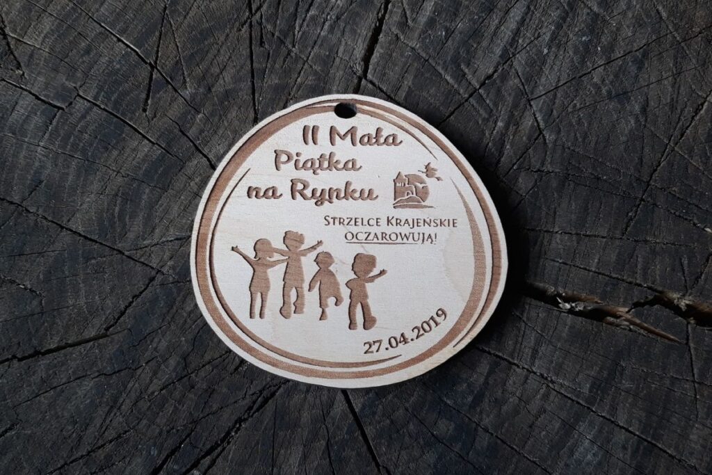 Drewniany medal pamiątkowy dla dzieci, biegi dziecięce Mała Piątka na Rynku, ekologiczne trofeum z grawerem postaci biegaczy.