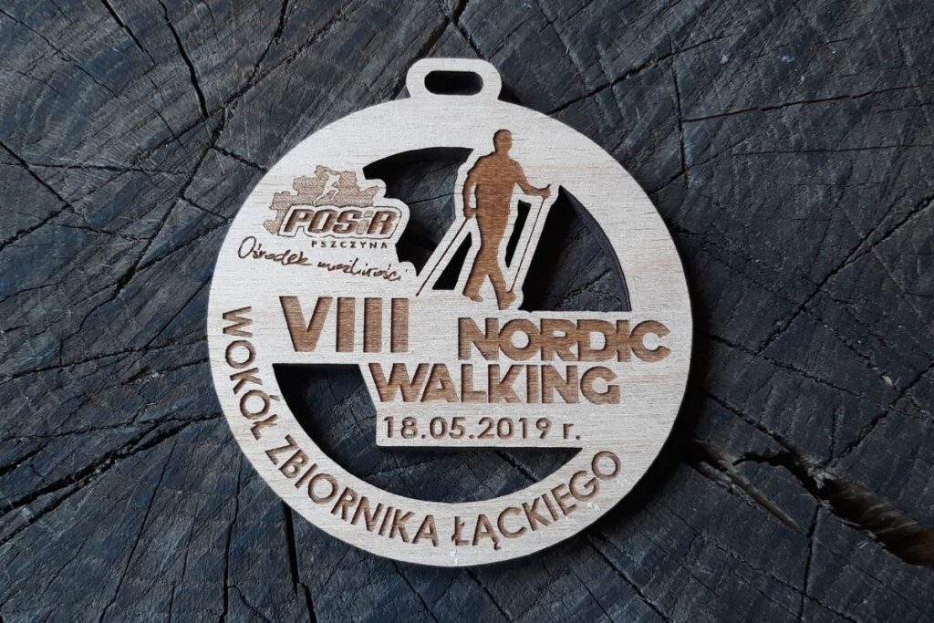 Drewniany medal Nordic Walking z ażurowymi wycięciami, przedstawiający sylwetkę maszerującej osoby z kijkami.